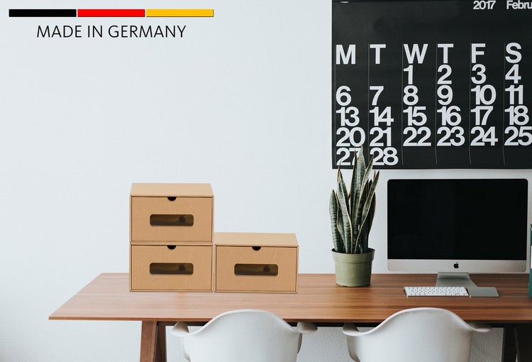 Drei Aufbewahrungsboxen aus Pappe mit Sichtfenster auf einem Schreibtisch mit Computer und Zimmerpflanze und Hinweis Made in Germany