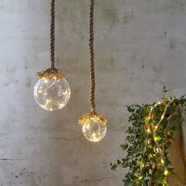 Zwei Hängeleuchten mit Seilaufhängung und Glaskugeln mit Lichterketten.