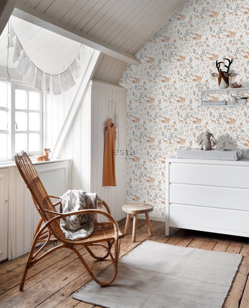 Helles Kinderzimmer mit Wickeltisch, Rattansessel und Tapete mit Tiermotiven