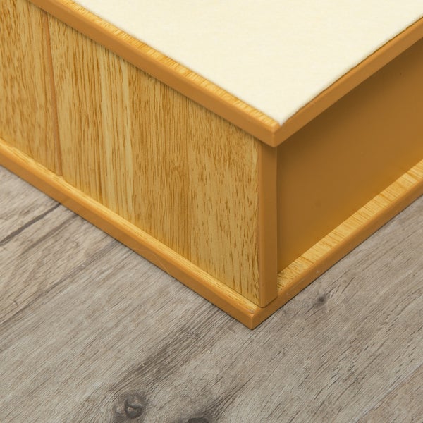 Nahaufnahme eines Eckdetails in Holzoptik mit heller Oberseite und glatter Seitenwand auf einem Boden in Holzoptik.