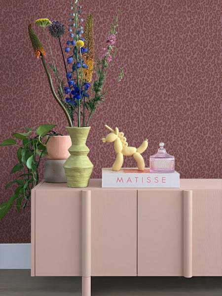 Vliestapete mit Leopardenmuster in einem modern gestalteten Raum. Ein Sideboard ist mit einer Vase, bunten Blumen und Dekoration stilvoll arrangiert.