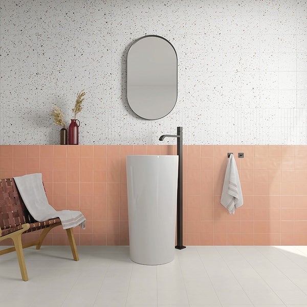 Modernes Badezimmer mit freistehendem Waschbecken, ovalem Spiegel und Fliesen in Terrazzo Optik sowie pfirsichfarbenen Wandfliesen.