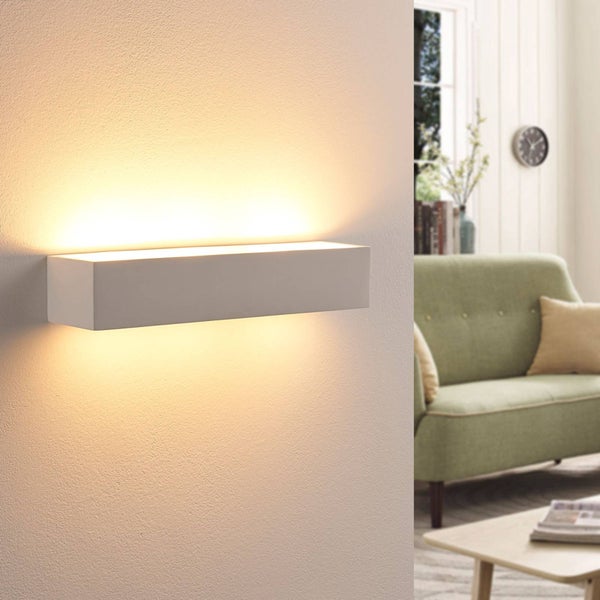 Rechteckige LED-Wandleuchte mit Up-and-Down-Lichteffekt an einer strukturierten Wand in einem modern eingerichteten Wohnzimmer mit Sofa.
