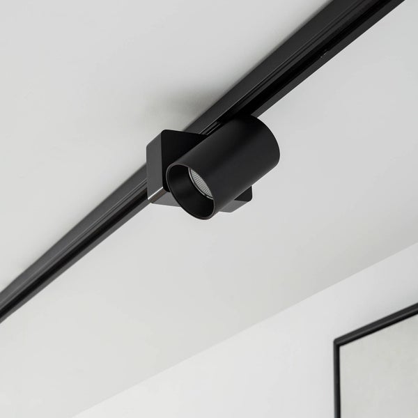 Schwarzer Strahler für Schienensystem, zylindrisches Design, an schwarzer Deckenschiene montiert.