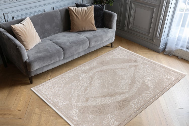 Ein moderner Wohnzimmerteppich mit orientalischem Muster auf einem Fischgrätparkettboden vor einem Sofa in einem elegant eingerichteten Wohnzimmer.