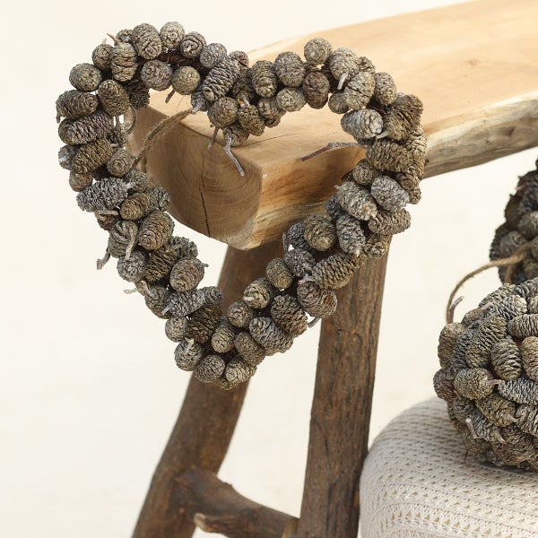 Dekoratives Herz aus Zapfen auf Holzbank