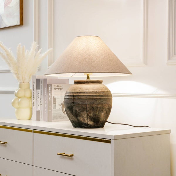 Tischleuchte mit beigem Lampenschirm auf einem Schrank