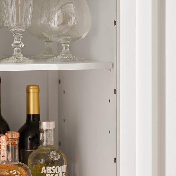 Detailansicht eines weißen Regals mit Gläsern und Flaschen