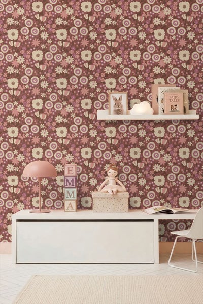 Kinderzimmer mit floral gemusterter Tapete, weißem Sideboard, Wandregal, Spielzeug und Tischlampe.