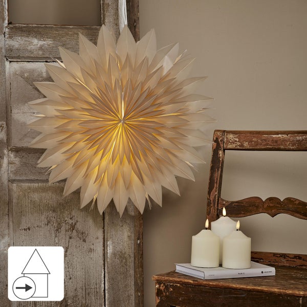 Dekorativer Papierstern an einer Holztür, daneben ein Hocker mit Kerzen