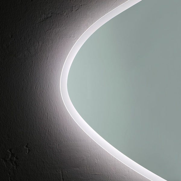 Detailansicht eines beleuchteten Badspiegels mit organischer Form und umlaufender LED-Beleuchtung an einer strukturierten Wand.