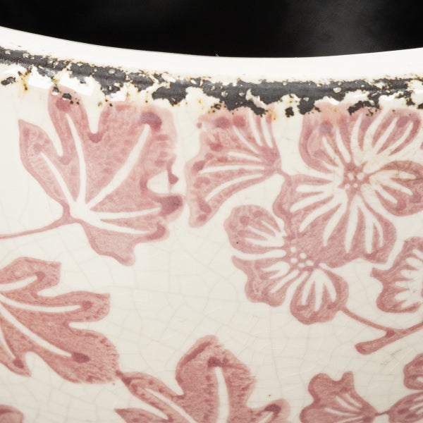 Nahaufnahme einer Keramikoberfläche mit Blüten- und Blattmuster, Craquelé-Glasur und strukturiertem Rand.