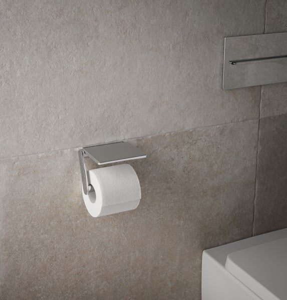 Ein moderner Toilettenpapierhalter mit Ablage aus Metall an einer Fliesenwand montiert.