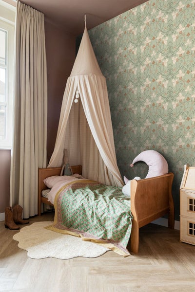 Kinderzimmer mit Holzbett, Stoffhimmel und floraler Tapete im Jugendstil. Heller Bodenbelag und lange Vorhänge.
