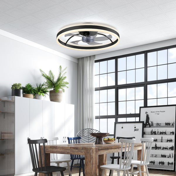 Moderner LED-Deckenventilator mit Licht in einem hellen Esszimmer mit Holztisch, verschiedenen Stühlen, großem Fenster und Pflanzen.
