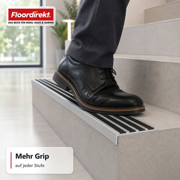 Treppenkantenprofil mit Antirutschstreifen an einer Steintreppe mit Fuß einer Person in einem Lederschuh und Floordirekt Logo.