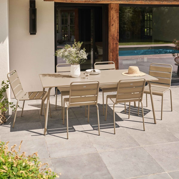 Modernes beiges Gartenmöbel-Set aus Metall mit rechteckigem Tisch und sechs Stühlen auf einer Terrasse neben einem Pool.