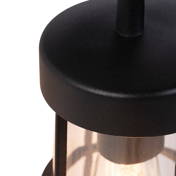 Nahaufnahme einer schwarzen Außenwandleuchte mit strukturierter Metallkappe und klarem Glasschirm.