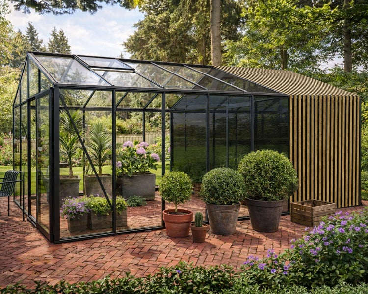 Modernes Gewächshaus mit schwarzem Rahmen, Glas und Holzlamellen auf einer Ziegelterrasse mit verschiedenen Topfpflanzen im Garten.