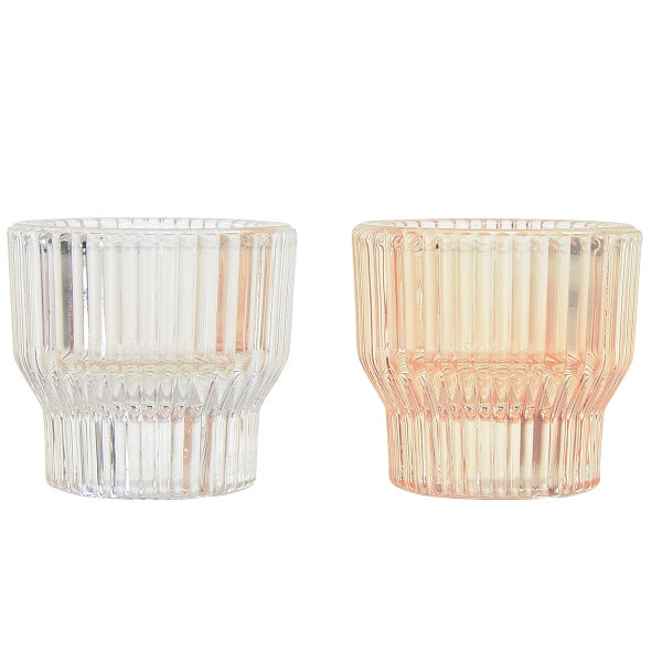 Zwei Teelichthalter aus Glas mit geriffelter Oberfläche, ein Stück transparent und ein Stück pfirsichfarben.