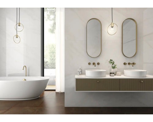 Modernes helles Badezimmer mit Wandfliesen in Marmoroptik, freistehender Badewanne, Doppelwaschtisch mit Aufsatzbecken und zwei ovalen Spiegeln.