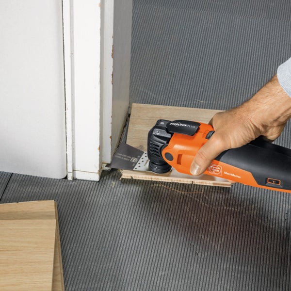 Handwerker schneidet mit einem Multifunktionswerkzeug ein Werkstück an einer Tür