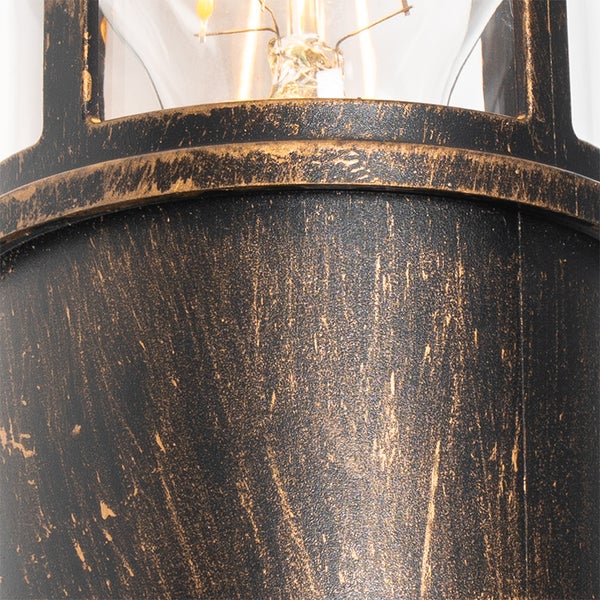 Detailaufnahme einer Leuchte aus Metall mit antikem Finish und Glaseinsatz inklusive sichtbarem Leuchtmittel.