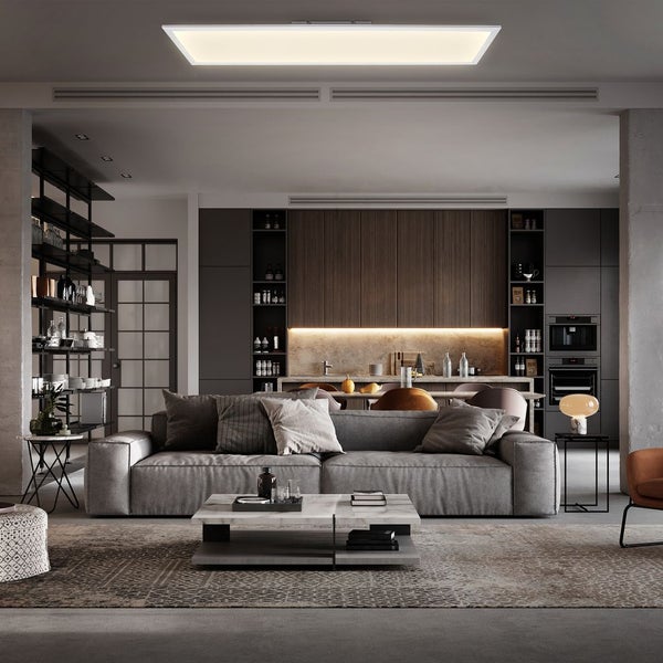 Modernes Wohnzimmer mit großem rechteckigem LED-Panel an der Decke, grauem Sofa und offenem Küchenbereich im Hintergrund.