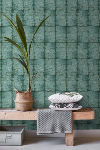 Dekorative Szene mit Pflanze im Korb, Kissen und Decke vor Wandtapete