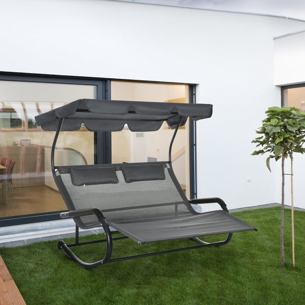 Moderne Doppel-Gartenliege mit verstellbarem Sonnendach und Kopfkissen auf einer Rasenfläche vor einem Wohnhaus. Stabiles Metallgestell mit Netzgewebe.