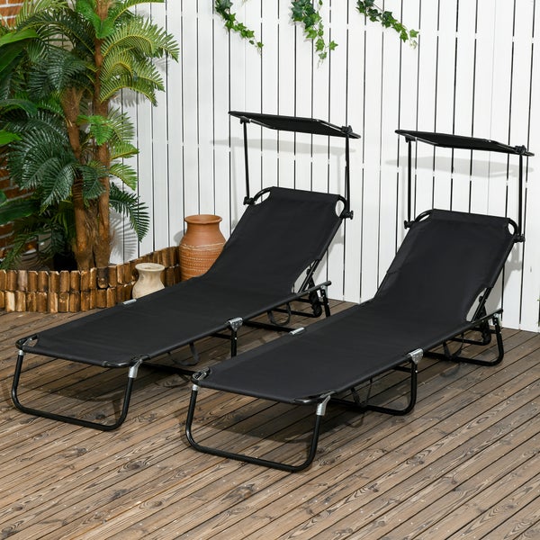 Zwei schwarze Gartenliegen mit verstellbarem Sonnendach auf einer hellen Holzterrasse vor einer weißen Wand mit Dekopflanzen.