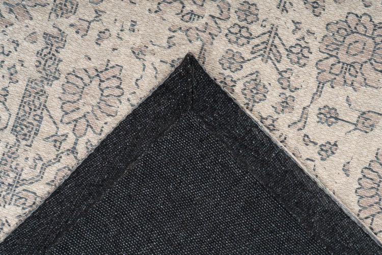 Nahaufnahme eines Orientteppichs mit Vintage-Blumenmuster, die die umgeklappte Ecke und die strukturierte Unterseite zeigt.