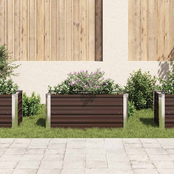 Hochbeet aus Metall mit geriffelten Seitenwänden und Metalleckpfosten, bepflanzt im Garten auf Rasen vor Holzzaun.