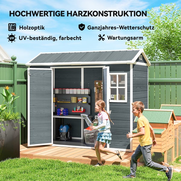 Grauer Geräteschuppen aus Kunststoff in Holzoptik im Garten mit Kindern. Offene Türen zeigen Regale mit Werkzeug. UV-beständig und wetterfest.
