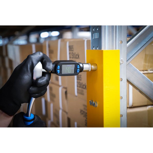 Hand mit Schutzhandschuh bedient digitalen Drehmomentschlüssel an einem Regal