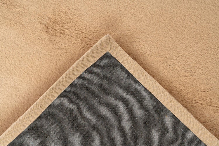 Detailansicht eines Teppichs mit weichem Flor, strukturierter Unterseite und sauber eingefasster Kante.