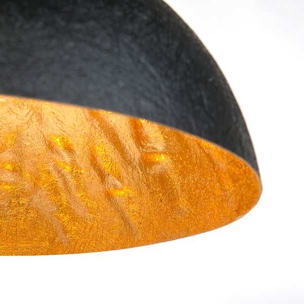 Detailaufnahme einer Hängelampe mit schwarzer Außenseite und goldfarbener Innenseite