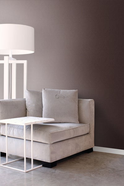 Einrichtungsszene mit einem Sofa, einem Beistelltisch und einer Stehlampe vor einer gemusterten Wand