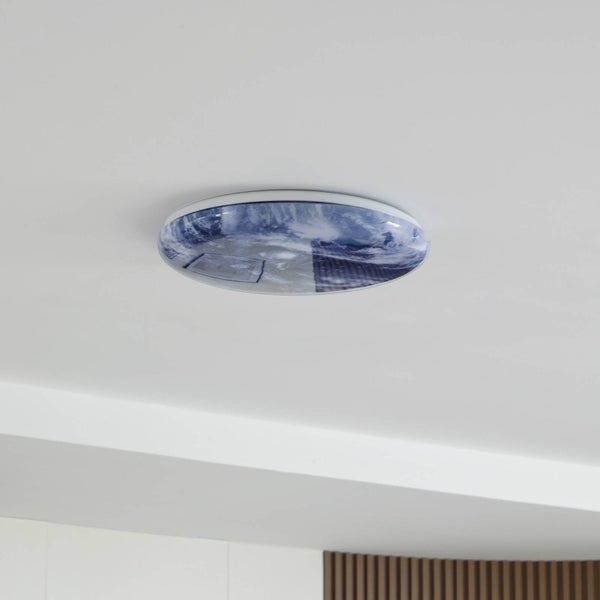 Runde LED-Deckenleuchte mit blau-weißem Wolkenmotiv montiert an einer weißen Zimmerdecke.