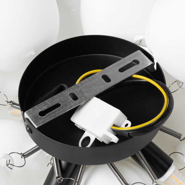 Innenansicht einer schwarzen Lampenhalterung mit Metallschiene, weißem Anschlussblock und Kabeln für die Deckenmontage.