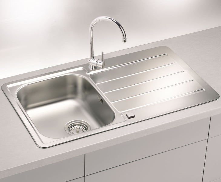 Einbau-Spüle aus Edelstahl mit einem Becken und Abtropffläche sowie einer montierten Küchenarmatur auf einer Arbeitsplatte.