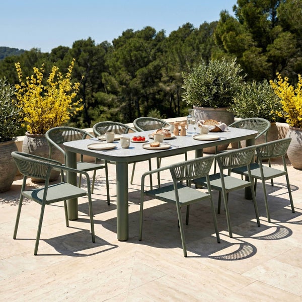 Gartenmöbel-Set bestehend aus einem rechteckigen Esstisch mit Steinoptik-Platte und acht Stühlen mit Seilgeflecht-Rückenlehne auf einer Terrasse.