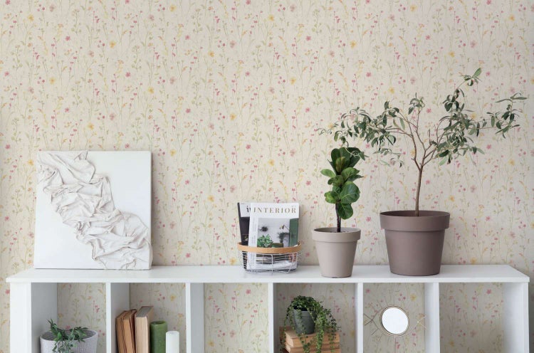 Wohnraum mit floraler Tapete mit Wildblumenmuster, dekoriert mit weißen Regalen, Pflanzen in Töpfen, einem Kunstwerk und Zeitschriften.