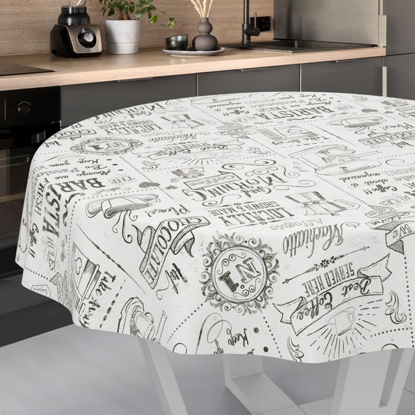 Runde Tischdecke mit Kaffee-Illustrationen und Schriftzügen auf einem Tisch in einer hellen, modern gestalteten Küche.