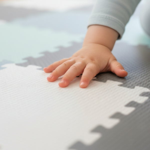 Babyhand auf einer gepolsterten Spielmatte mit Puzzleverbindung