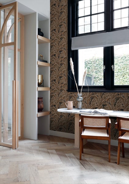 Wohnzimmer mit gemusterter Tapete, Esstisch und Bücherregal.