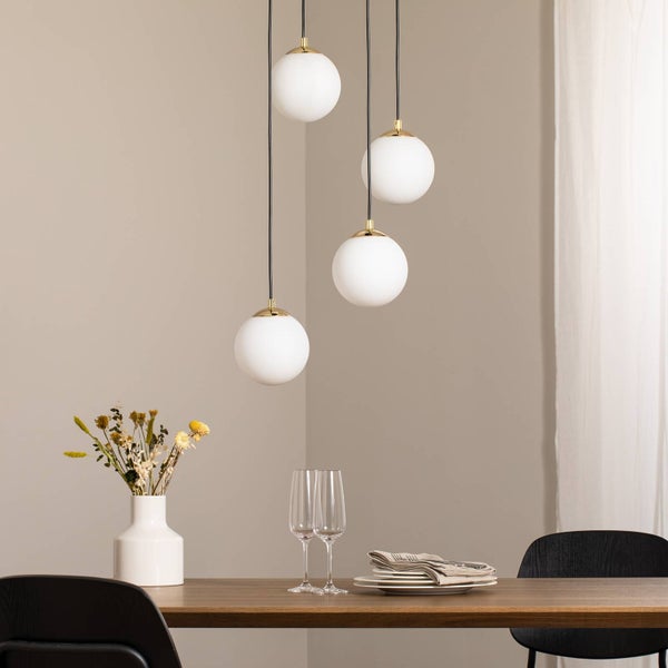 Hängelampe mit drei weißen Kugelschirmen über einem Esstisch