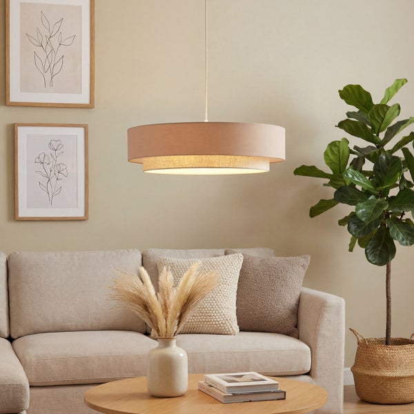 Moderne Wohnzimmerszene mit zweistufiger Textil-Pendelleuchte über einem beigen Sofa, einem Couchtisch aus Holz und einer großen Zimmerpflanze.
