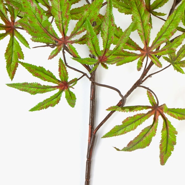 Künstlicher Ahornzweig mit grün-roten gezackten Blättern an einem braunen Stiel.