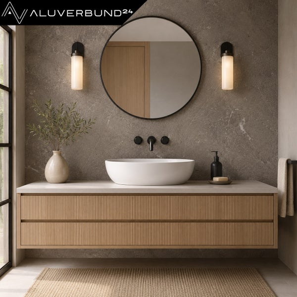 Modernes Badezimmer mit hängendem Holz-Unterschrank, weißem Aufsatzbecken, Rundspiegel und Wandpaneelen in Steinoptik. Alverbund24 Logo.